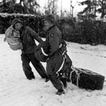 Two Sreaming Eagles drag airdropped supplies near Bastogne